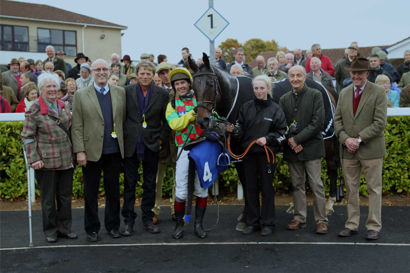 A jockey with his horse and a small crowd of people